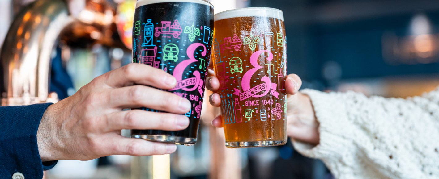 Two people with pints doing cheers